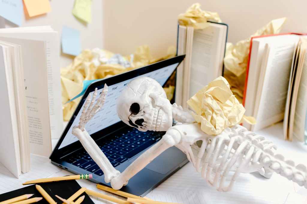 white skeleton figurine suffering from burnout  on black laptop computer